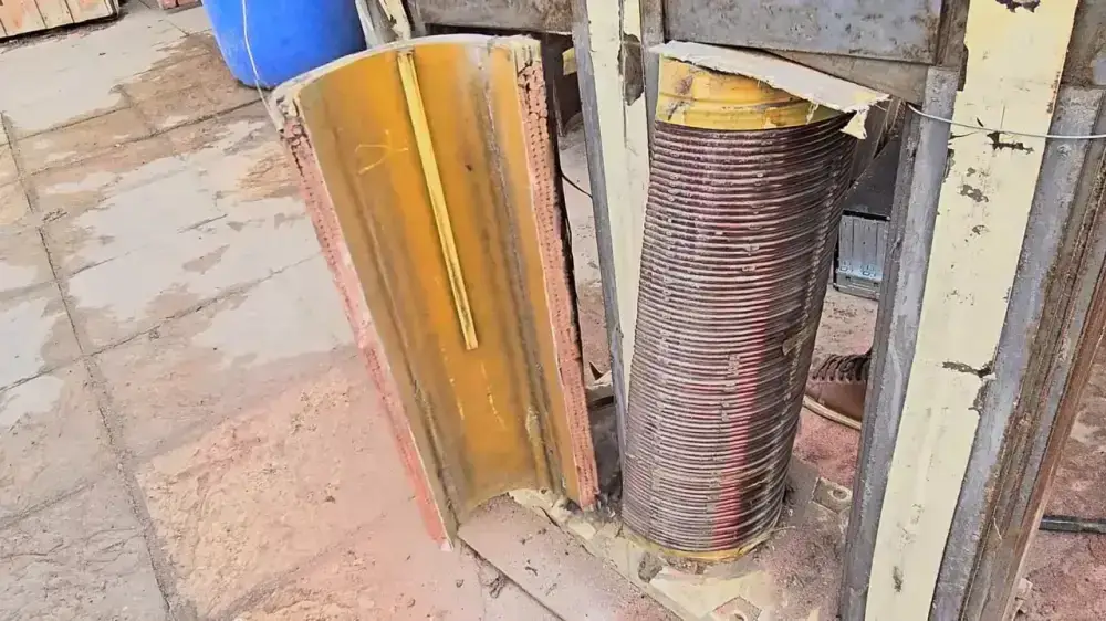 Large copper winding coil exposed inside the transformer frame beside a yellow insulation panel