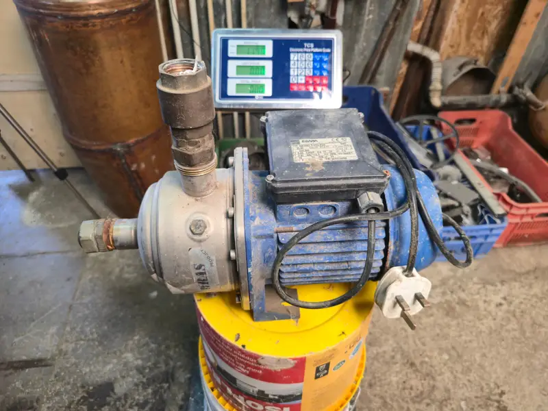 Complete electric water pump with blue motor housing, attached pipe fittings, and power cable before dismantling.
